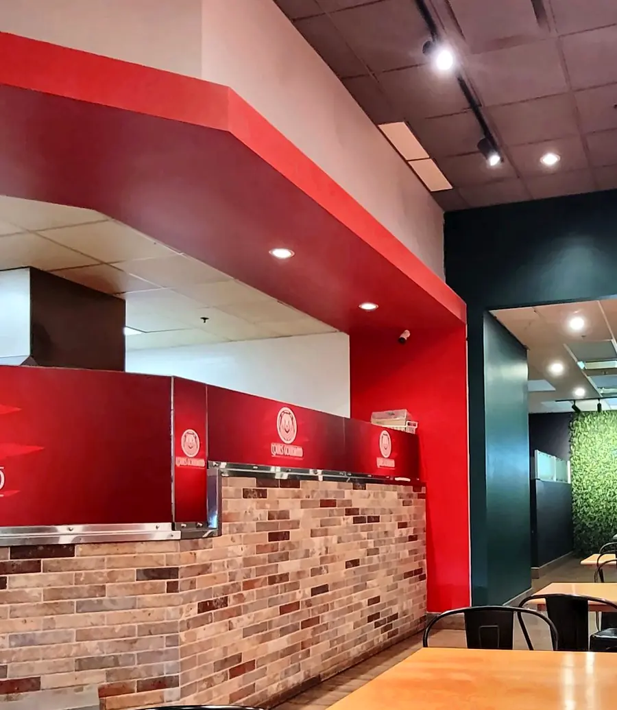 Le comptoir de commande en brique et panneaux rouges au logo, et les tables de bois.